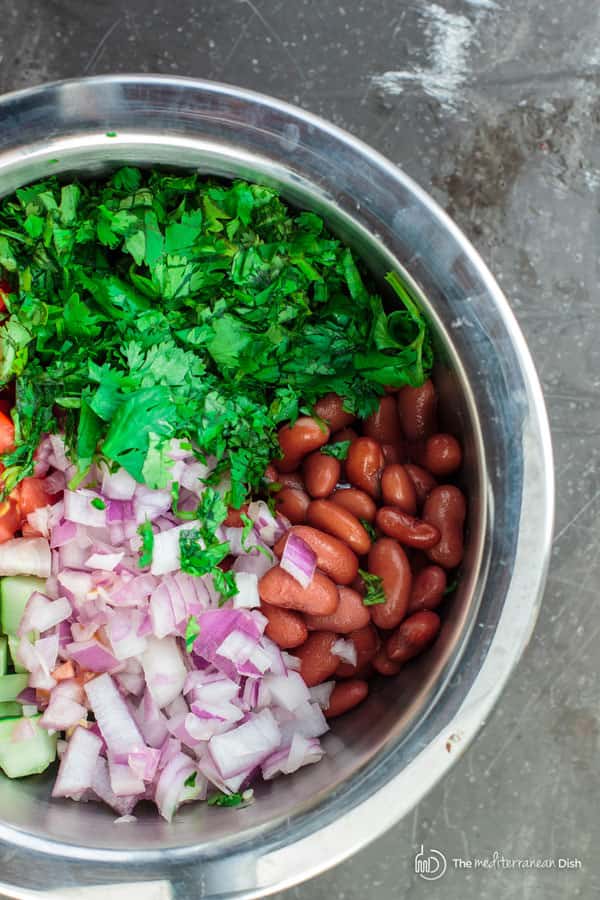 Kidney beans, onions, cucumbers, tomato and fresh herbs in one large mixing bowl