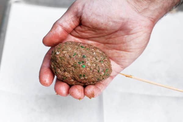 Molding meat mixture onto wooden skewers for kofta kebabs