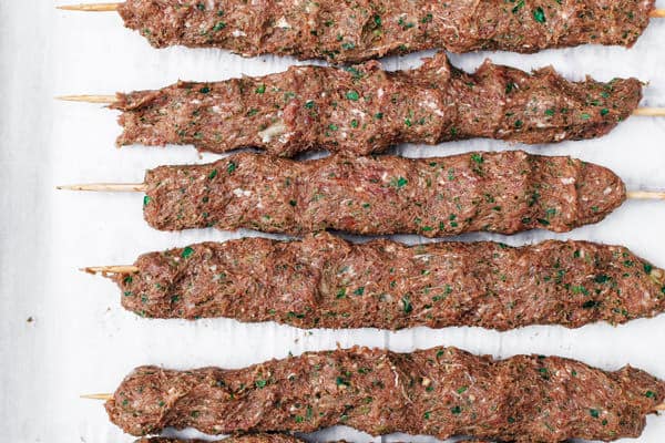 Raw kofta kebabs assembled on tray before grilling