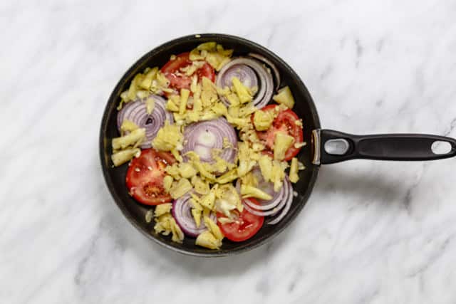 Zucchini insides, tomato and onion in a pan
