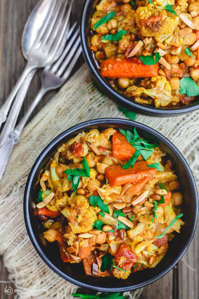 Turmeric Roasted Cauliflower and Chickpea Stew Recipe (tutorial)| The Mediterranean Dish. A delicious vegan, gluten free chickpea stew that is hearty, healthy and flavor-packed. Roasted cauliflower and carrots are added with chickpeas and spices in a chunky tomato sauce. Easy Mediterranean recipe with step-by-step tutorial from TheMediterraneanDish.com