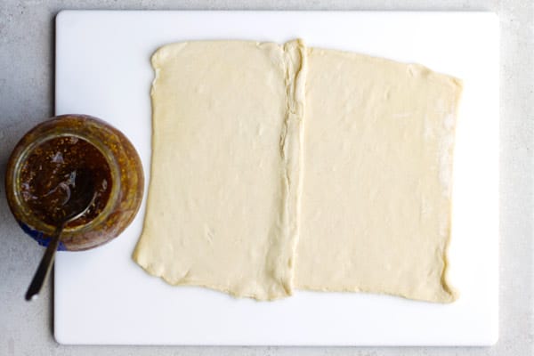 Sheet of puff pastry rolled out flat with jar of jam on side