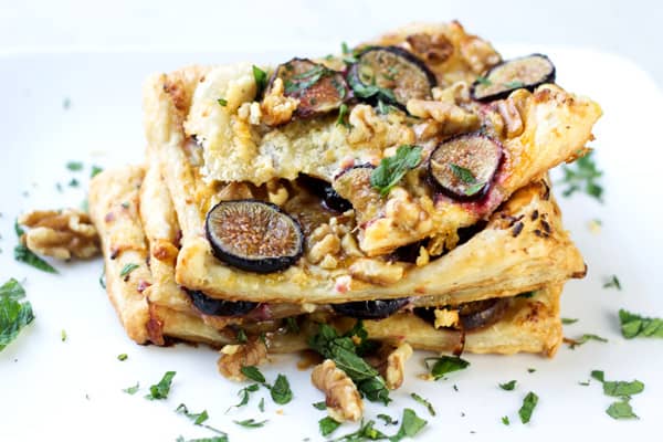 Layers of fig puff pastry garnished with walnuts and fresh parsley