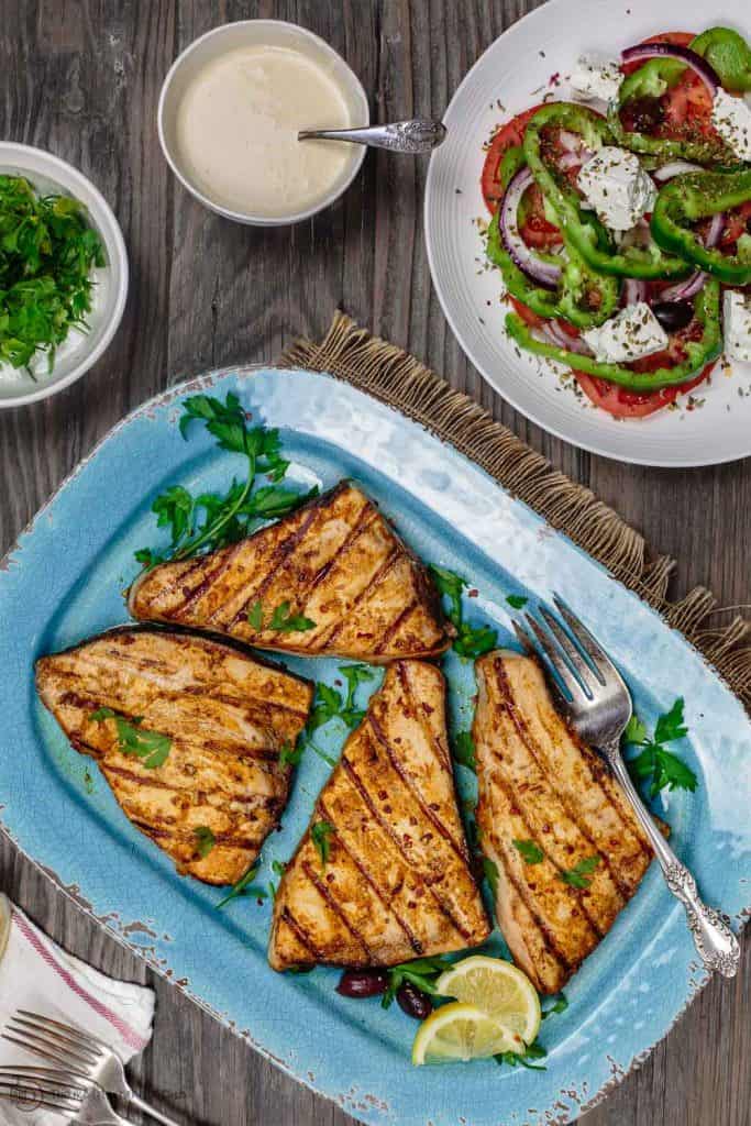 grilled swordfish served with greek salad and a side of tahini