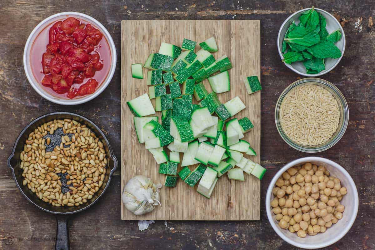 Ingredients for orzo recipe. zucchini, chickpeas, tomatoes, orzo, fresh mint, garlic and toasted pine nuts