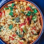 Orzo with zucchini, chickpeas, and tomatoes. Garnished with fresh mint and toasted pine nuts