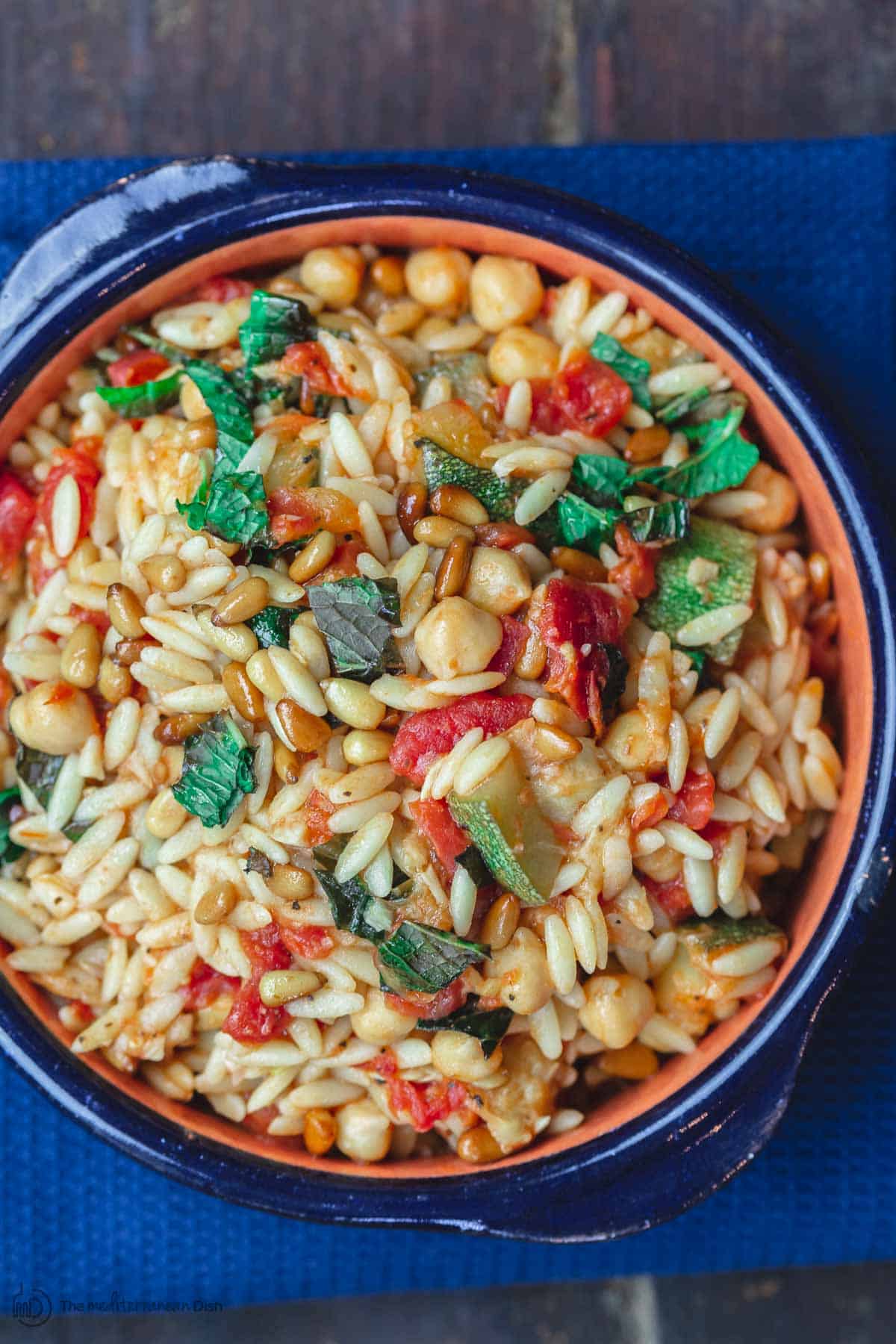 Orzo with zucchini, chickpeas, and tomatoes. Garnished with fresh mint and toasted pine nuts