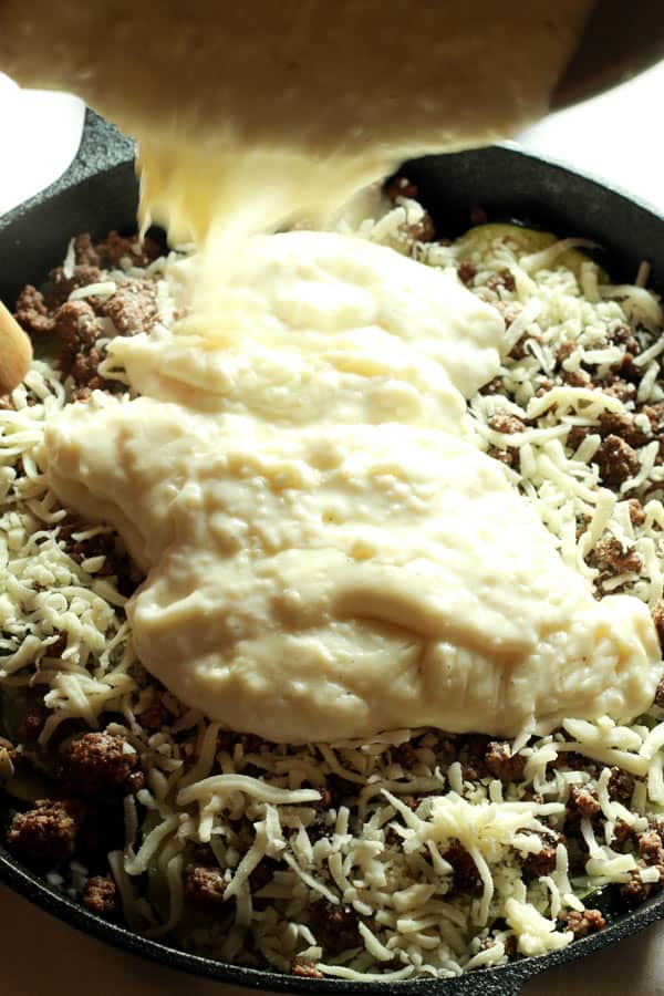 bechamel sauce poured on top of Zucchini Casserole