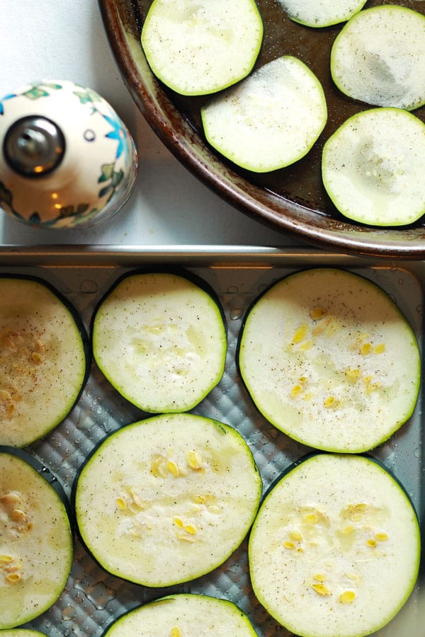 Zucchini slices in a pan drizzled with olive oil
