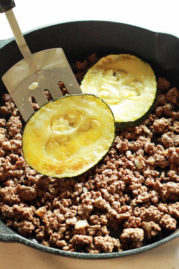 Cooked zucchini slices added to pot of browned ground beef