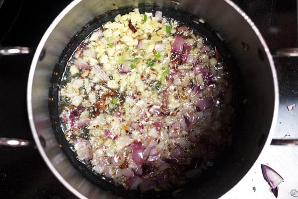 Pepper and onion being sauteed in a pot
