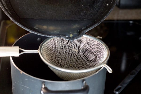 Pouring broth into the pot using a strainer