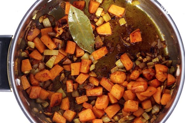 Pot containing olive oil, onions, sweet potato and celery 