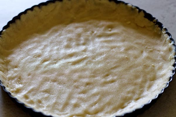 Dough pressed down to form thin layer in baking pie dish