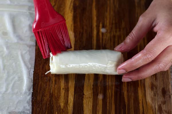 Brushing meat rolls with egg wash