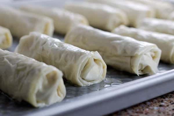 Brushed meat rolls lined on a baking pan