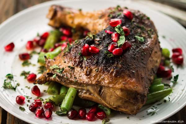 Pomegranate chicken thighs served on a plate and garnished with extra pomegranate seeds