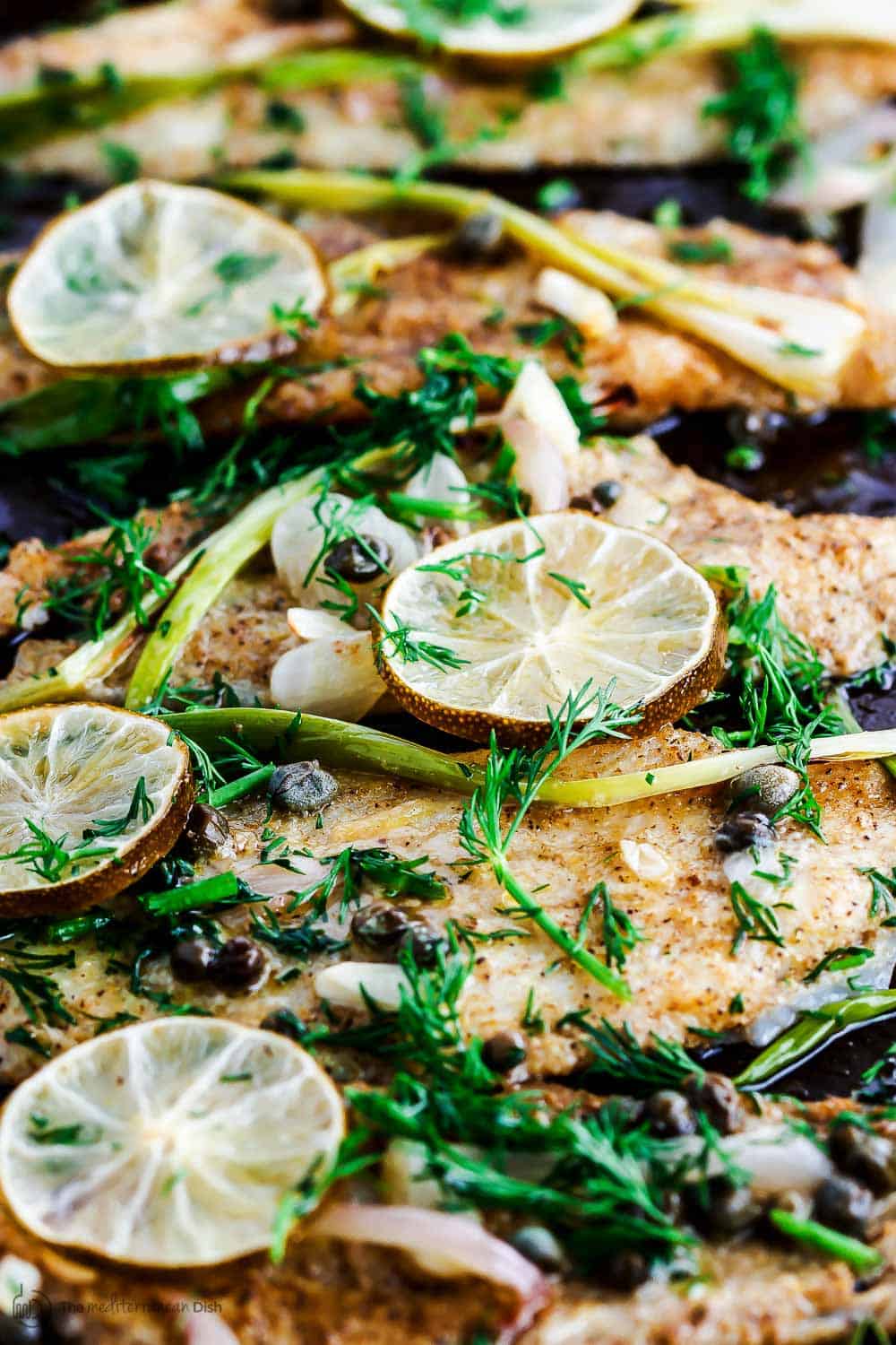 Sole fillet garnished with olive oil, capers, dill and lemon slices