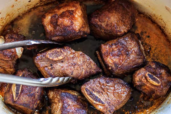 Beef chunks being cooked in oil in a pot