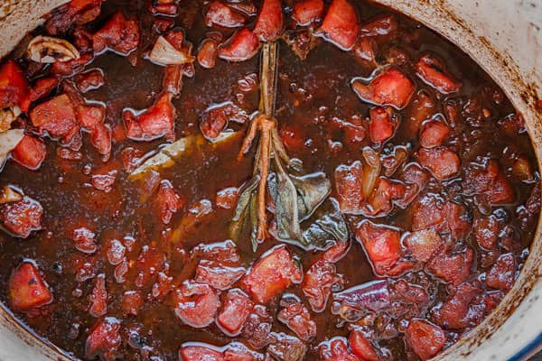 Diced tomatoes, garlic, sage, and bay leaves are added to the pot