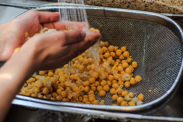 chickpeas being peeled under running water