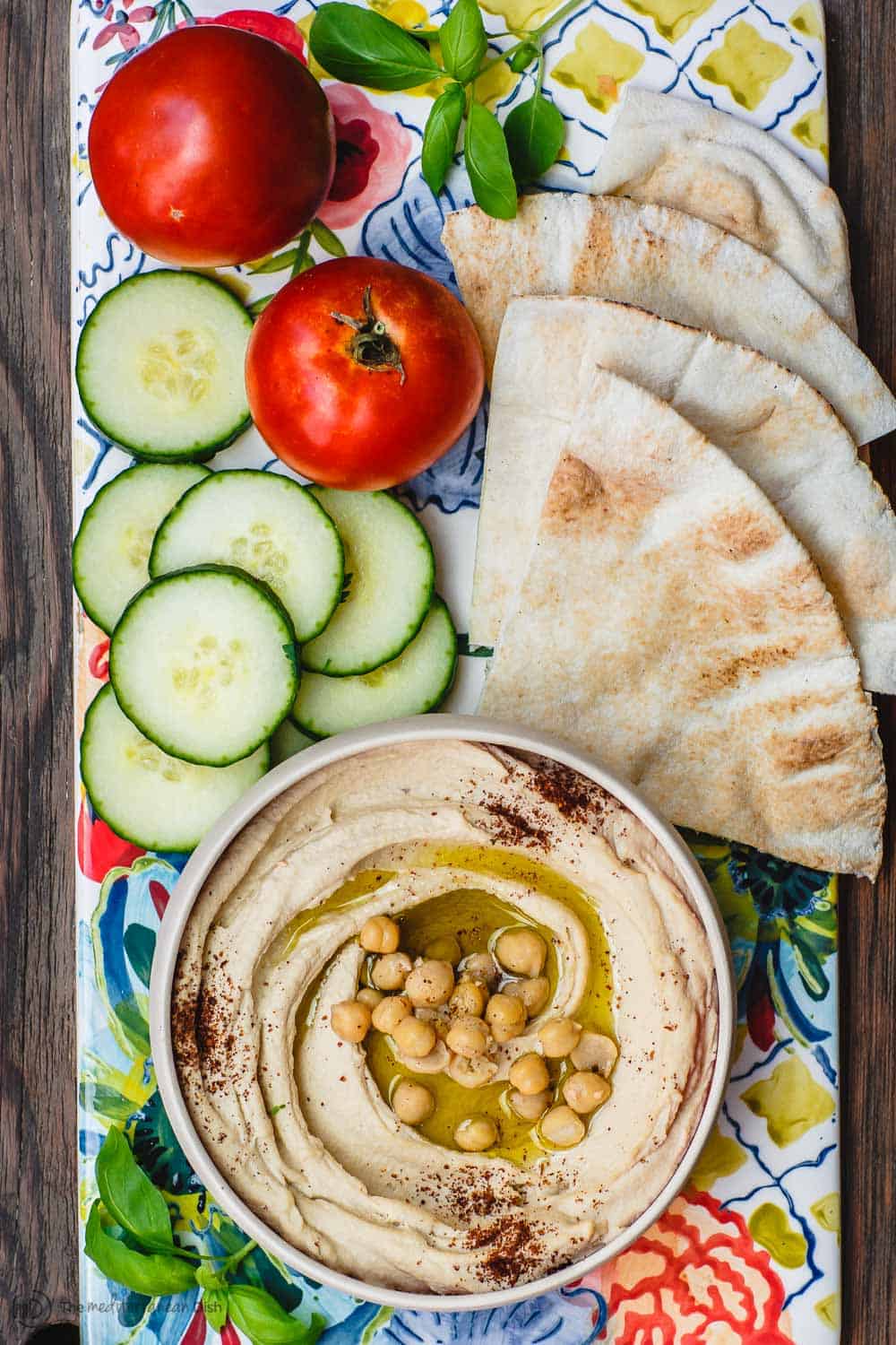 Hummus served with pita bread and sliced cucumbers and tomatoes