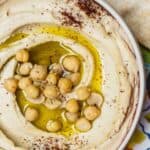 bowl of hummus with olive oil and chickpeas. A side of pita bread