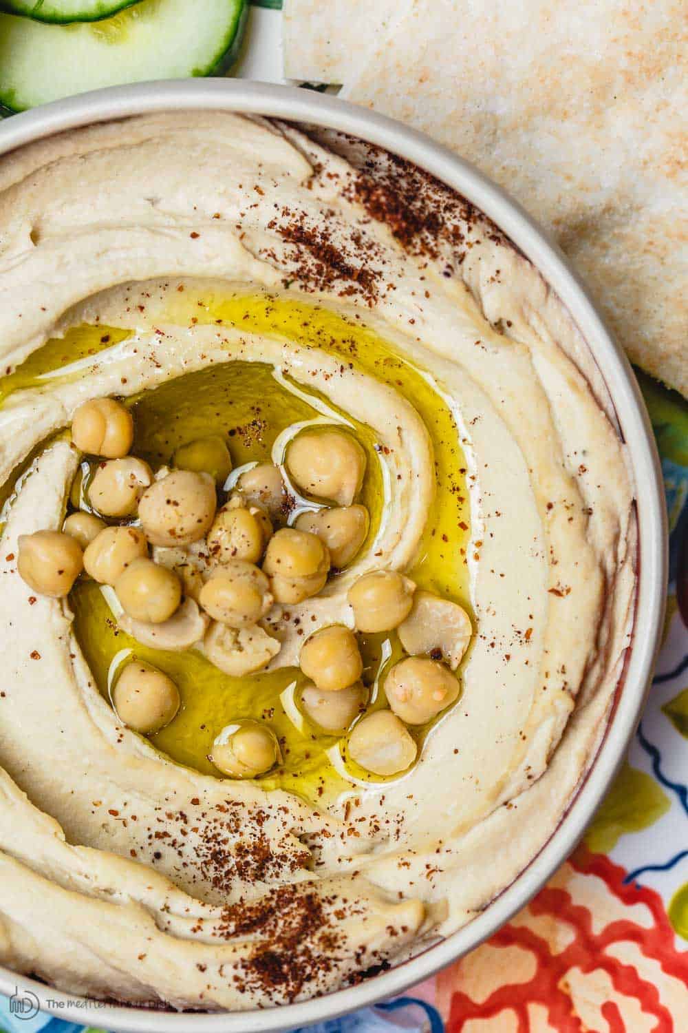 bowl of hummus with olive oil and chickpeas. A side of pita bread