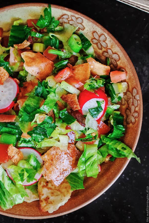 Fattoush garniert mit Stücken Fladenbrot, Tomaten und anderem Gemüse