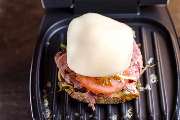 Assemble the components on a table-top grill, including the bread, roast beef, tomato, vegetables and cheese