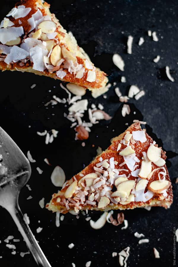 Slices of Basbousa garnished with coconut and sliced almonds
