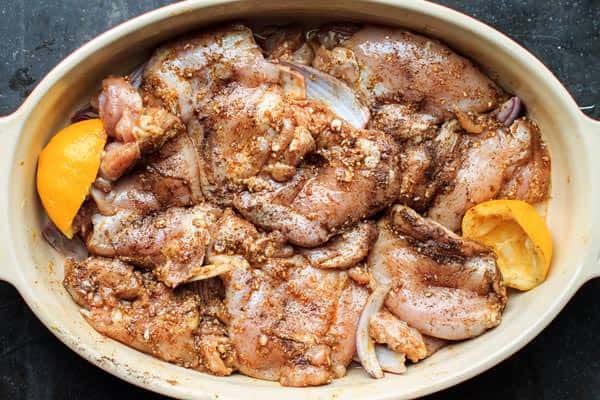 Raw chicken being marinated in a dish