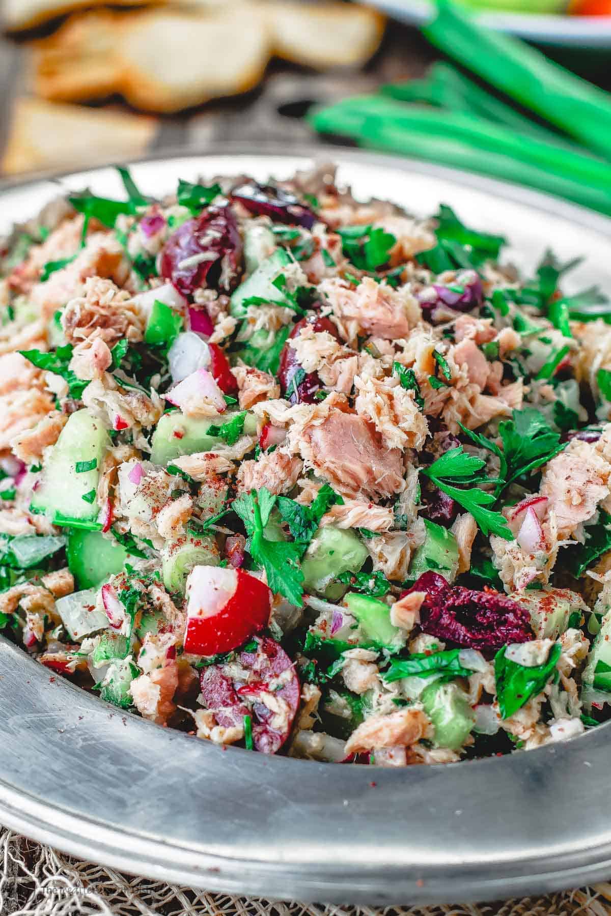 Mediterranean Tuna Salad with fresh herbs, chopped vegetables and Dijon vinaigrette on a plate