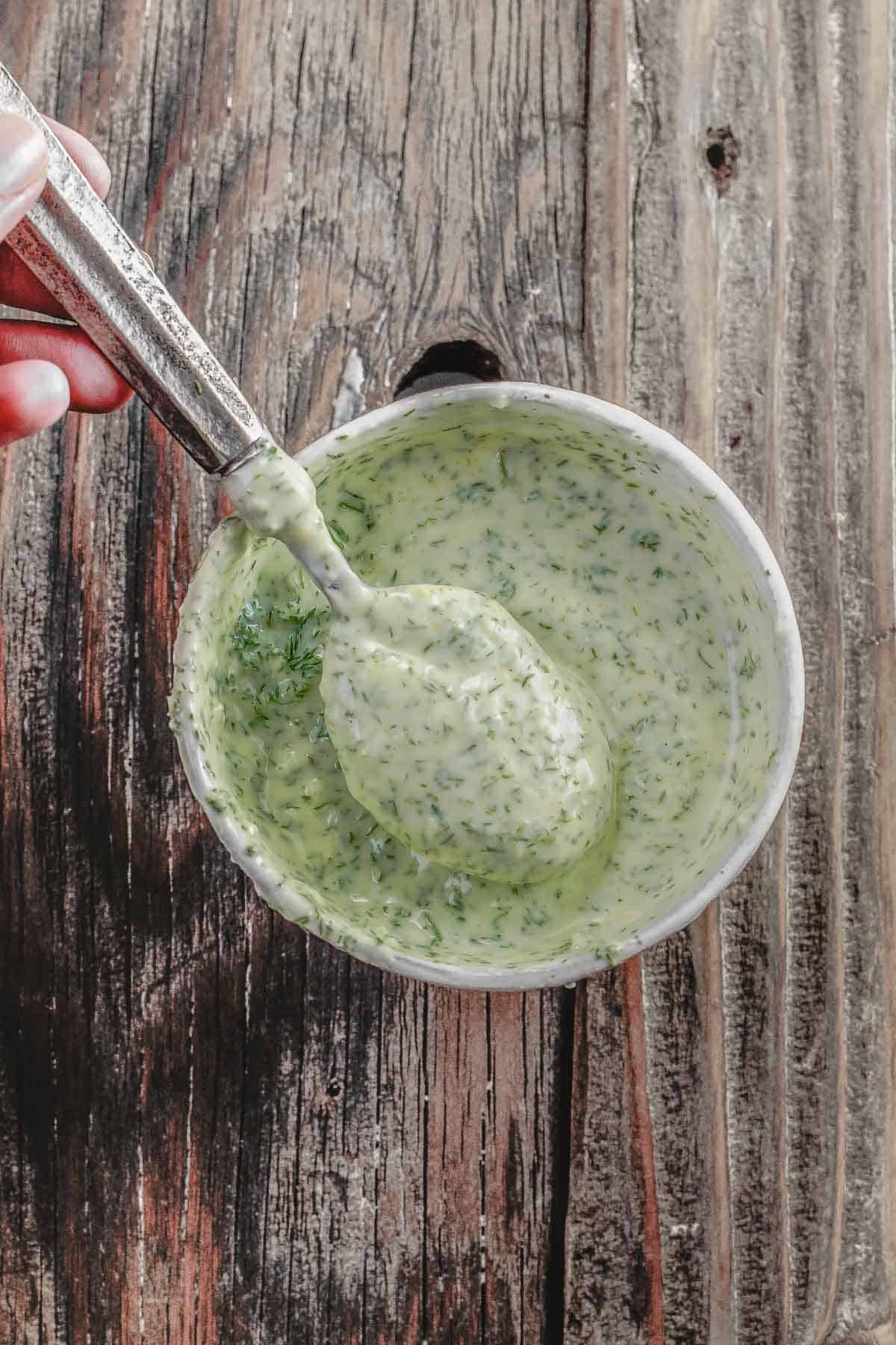 Dill greek yogurt sauce for grilled chicken in a small white bowl with a spoon