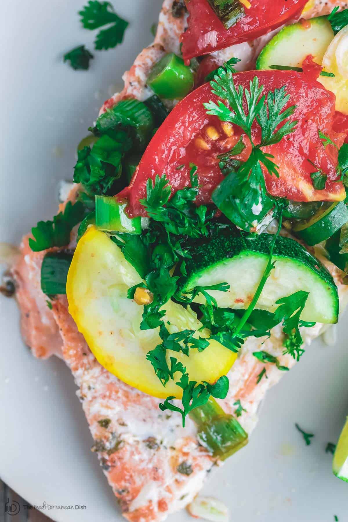 Mediterranean-style Oven Baked Salmon in Foil | The Mediterranean Dish. Salmon with garlic and thyme, topped with vegetables and a buttery-lime sauce and baked in foil to perfection! Bakes in less than 25 mins! Try this easy dinner soon.