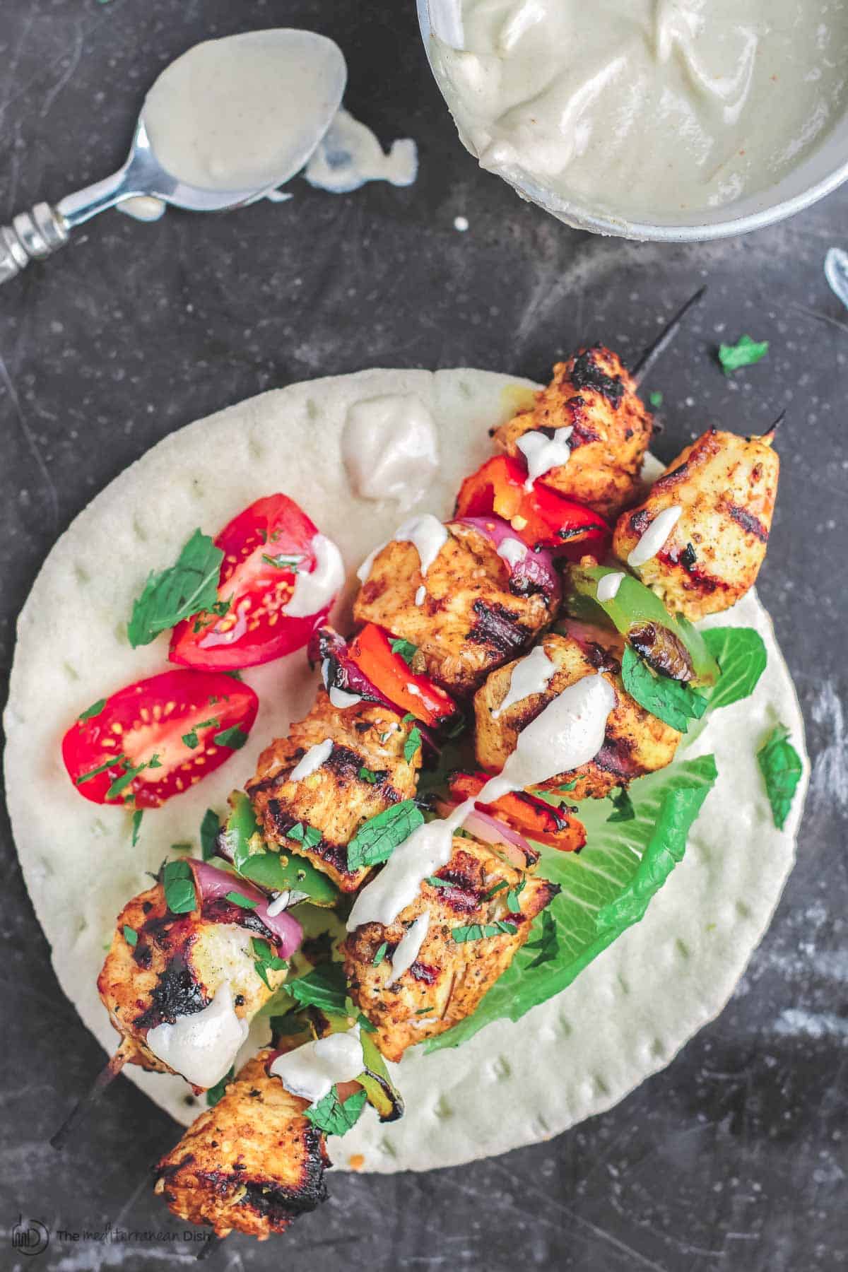 Grilled chicken kabobs served on flatbread with tahini sauce