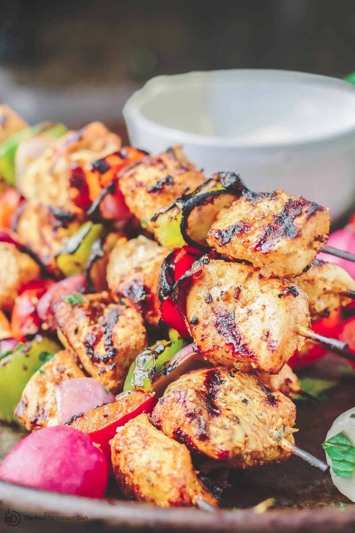 Grilled chicken kabob stacked on top of each other on a serving dish.