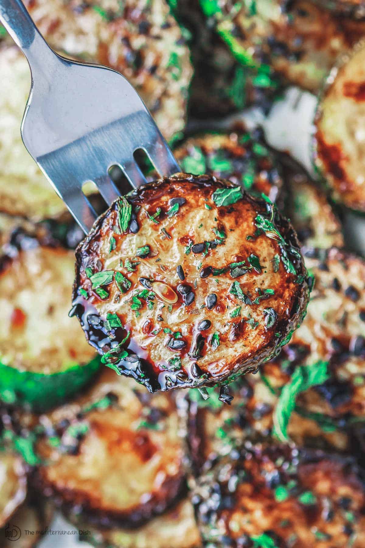 Sauteed zucchini on fork with balsamic glaze and black sesame seeds