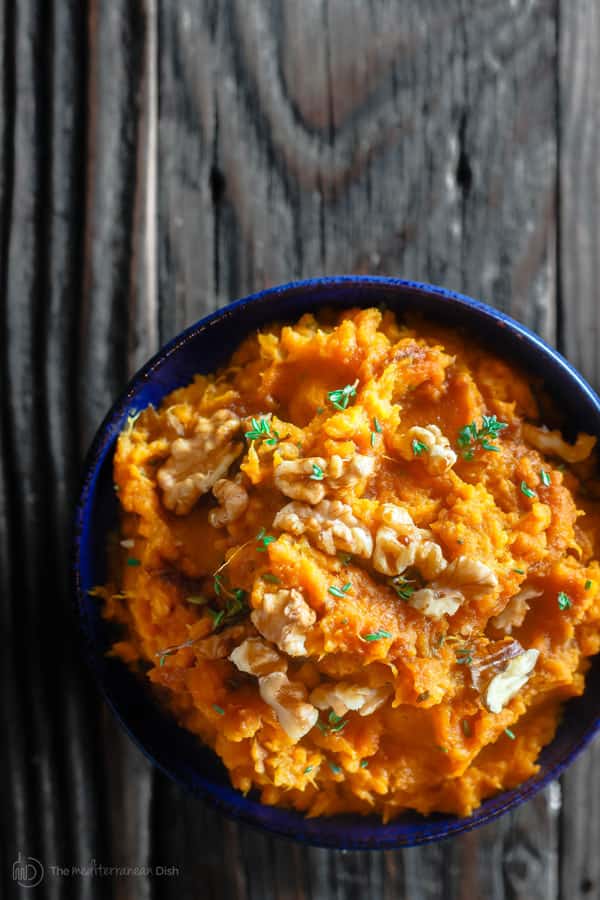 Mashed Sweet Potato served in a bowl with walnuts as a garnish