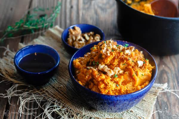 Bowl of Roasted Mashed Sweet Potatoes with molasses and extra walnuts on the side