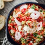 Shrimp Bruschetta Recipe | The Mediterranean Dish. Not your average bruschetta. Fresh tomatoes tossed with shrimp, avocado, green onions, garlic and a good quality basil pesto! A festive and more satisfying appetizer in minutes.