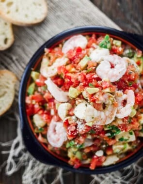Shrimp Bruschetta Recipe | The Mediterranean Dish. Not your average bruschetta. Fresh tomatoes tossed with shrimp, avocado, green onions, garlic and a good quality basil pesto! A festive and more satisfying appetizer in minutes.