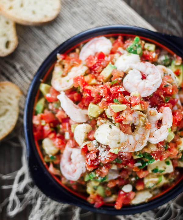Shrimp Bruschetta Recipe | The Mediterranean Dish. Not your average bruschetta. Fresh tomatoes tossed with shrimp, avocado, green onions, garlic and a good quality basil pesto! A festive and more satisfying appetizer in minutes.
