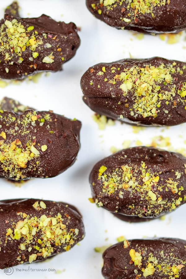 Chopped pistachios are used to garnish the tops of the chocolate covered dates
