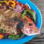 Mediterranean Whole Roasted Red Snapper with Garlic and Bell Peppers | The Mediterranean Dish. An easy recipe your family will love! Whole snapper stuffed with fresh garlic, dill, bell peppers, tomatoes and onions and roasted to perfection. Add a salad or a quick rice and you're good to go! Ready in 30 minutes!