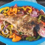 Roasted whole red snapper with vegetables served on a large dish
