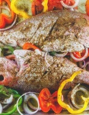 Whole red snapper with spices and vegetables prepared in a large baking sheet