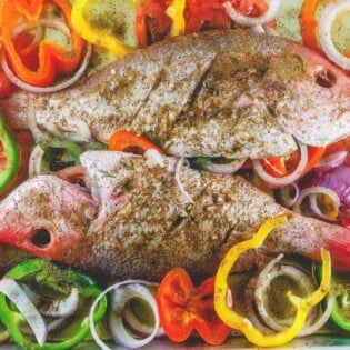 Whole red snapper with spices and vegetables prepared in a large baking sheet