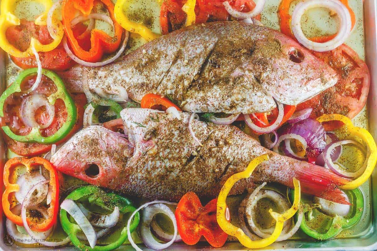 Whole red snapper with spices and vegetables prepared in a large baking sheet