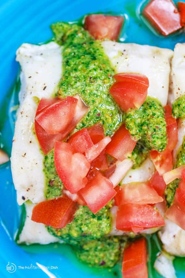Pesto and tomatoes drizzled over baked cod
